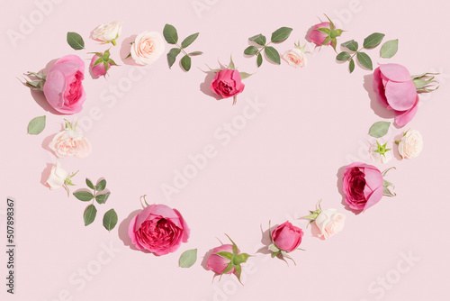 Creative flowers composition. Heart symbol made of pink rose flowers on pastel pink background. Minimal flat lay. © lagano