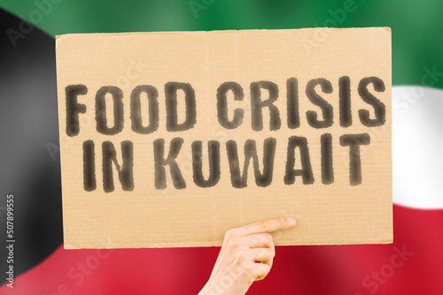 The phrase " Food crisis in Kuwait " is on a banner in men's hands with a blurred Kuwaiti flag in the background. Crisis. Finance. Life. Nutrition. Bread. Disaster. Collapse. Social issue