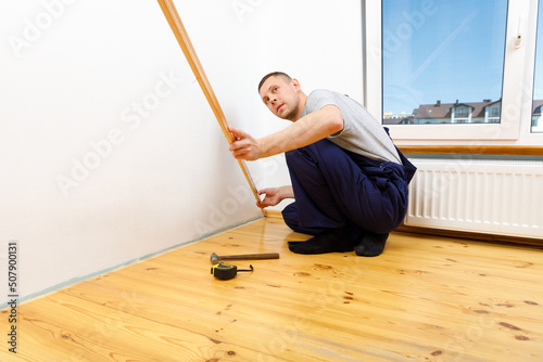 To make repairs. Installing a new skirting board. a man makes repairs in a room