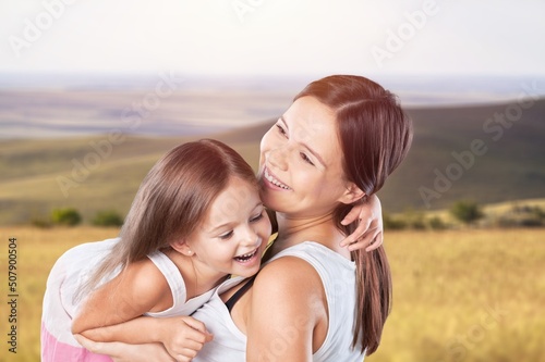 Little child daughter hugging mother while standing in the middle of the field.
