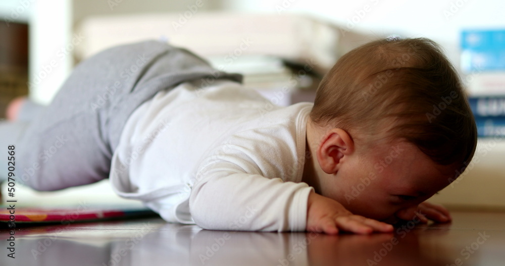Baby infant lying on floor starts to cry. Upset angry toddler boy Baby infant lying on floor starts to cry. Upset angry toddler boy
