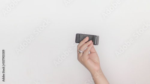 Hand holding a black cell phone holder, on white background.