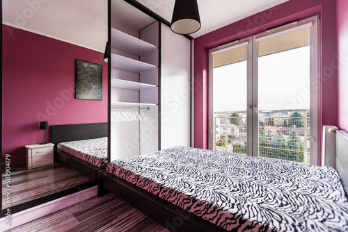 Stylowa sypialnia z dużym łóżkiem i fioletowymi ścianami © adr77