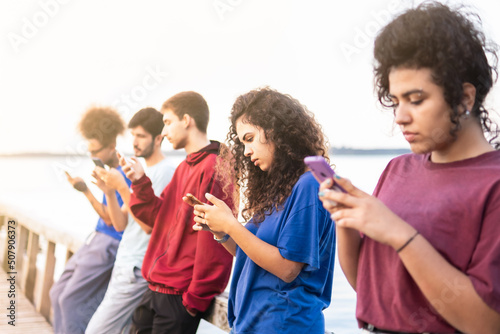 Group of multiracial friends using smartphones to sharing content on social networks. Technology lifestyle concept - Selective focus.