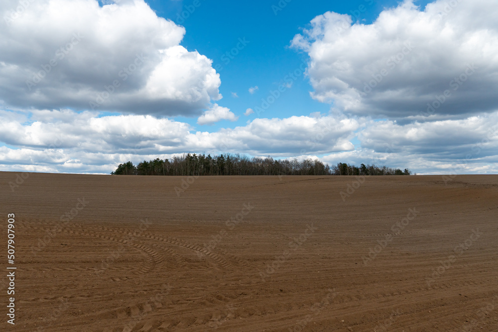 A plowed field against the sky. The season of planting crops in a wheat field. Preparing the field for planting rapeseed, wheat, rye and barley in rural areas. A plowed field against the sky. The season of planting crops in a wheat field. Preparing the field for planting rapeseed, wheat, rye and barley in rural areas.