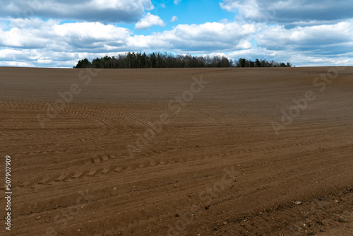 A plowed field against the sky. The season of planting crops in a wheat field. Preparing the field for planting rapeseed  wheat  rye and barley in rural areas.