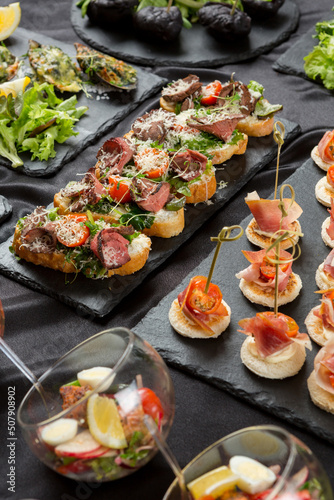 Festive appetizer. A set of bruschetta with roasted beef, cherry tomatoes and grated cheese, as well as toasted canapes with bacon, cherry tomatoes and cream cheese 