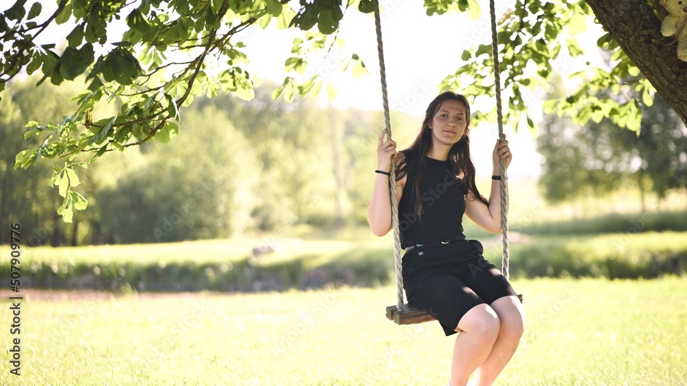 Young beautiful long-haired girl on a rope swing.