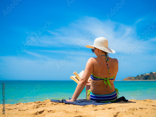 Woman sitting on beach reading book

