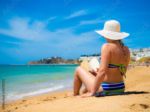 Woman sitting on beach reading book 