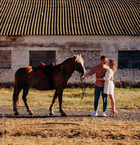 Loving couple with brown horse on ranch at summer