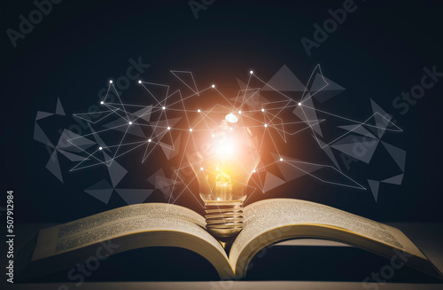 Thinking and creative concept, Light bulb on the Book and light bulb style bokeh vintage dark background,Concept The idea of reading books, knowledge, and searching for new ideas. photo