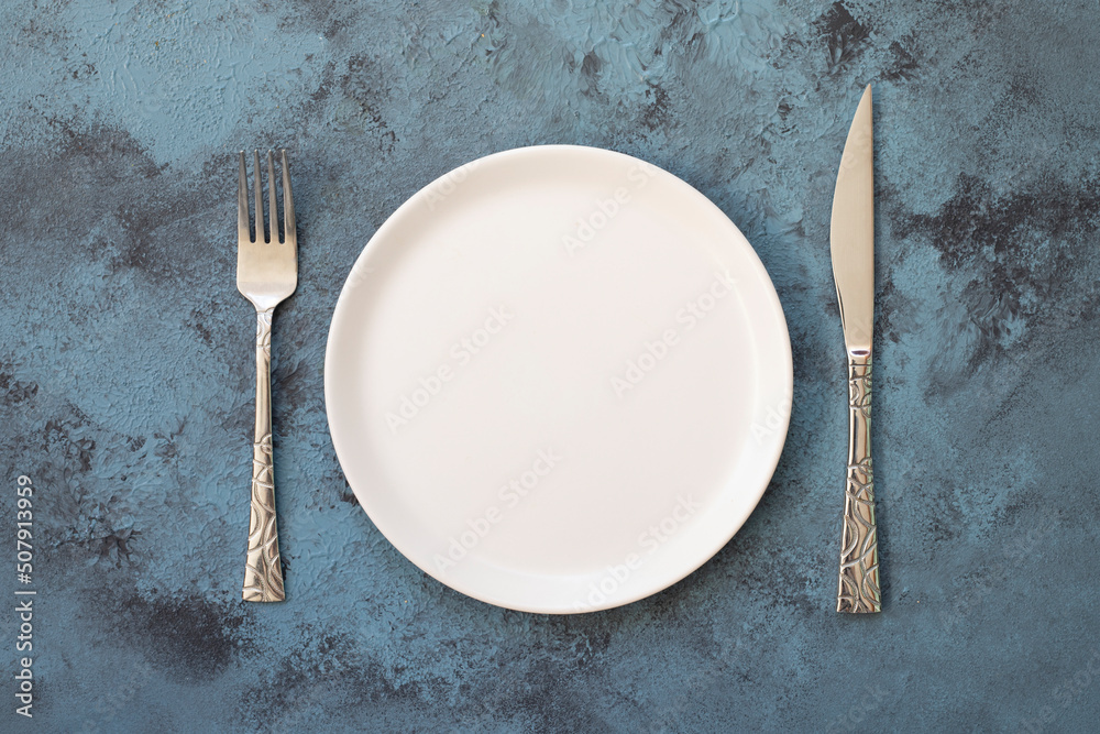 Empty white plate on blue concrete background. Top view, with copy space Empty white plate on blue concrete background. Top view, with copy space