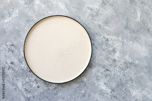 Empty white plate on gray concrete background. Top view, with copy space