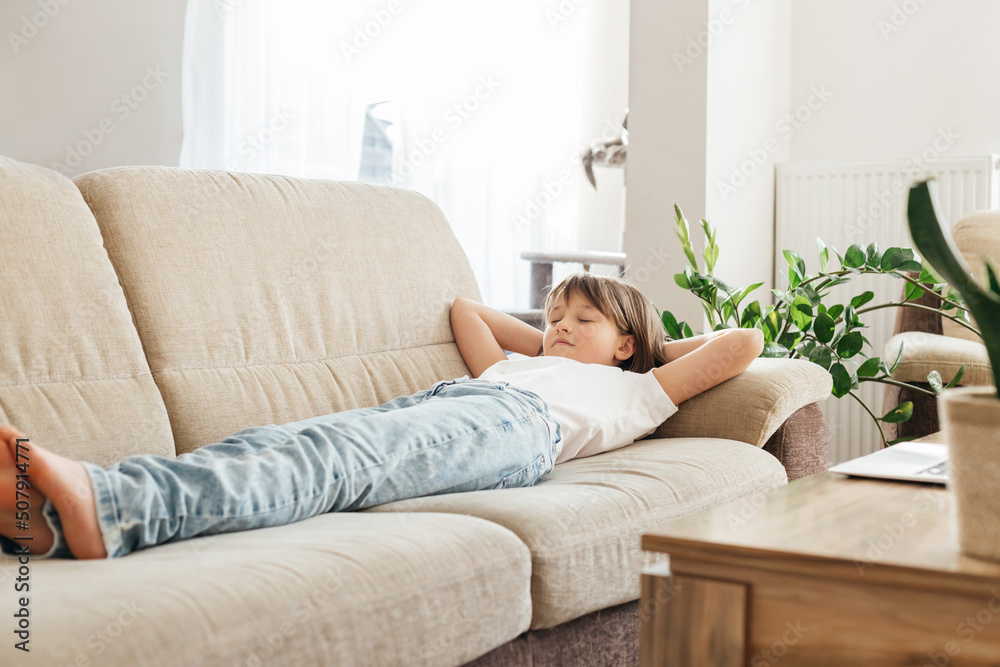 Happy teenage girl, schoolgirl is resting in the room on a comfortable sofa. Child lies and dreams, weekend at home Happy teenage girl, schoolgirl is resting in the room on a comfortable sofa. Child lies and dreams, weekend at home