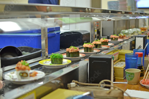 Plates of spicy tuna sushi and other varieties during a quick lunch on a conveyor belt at a kaitenzushi style restaurant