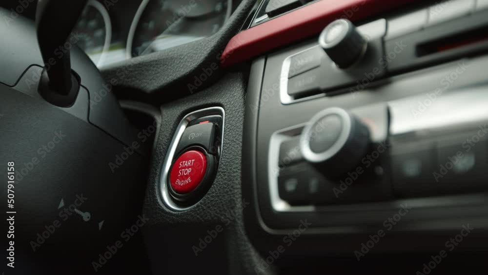 A female finger with a red manicure presses the red car start button and starts the sport automobile. Slow motion pressing the ignition button of a modern keyless car. 4k footage A female finger with a red manicure presses the red car start button and starts the sport automobile. Slow motion pressing the ignition button of a modern keyless car. 4k footage