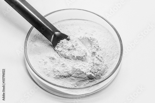 Petri dish with powdered Benzoyl Peroxide, used in the preparation of cream, lotion or gel in the treatment of acne and mild and moderate forms of dermatitis. Isolated white background, copy space photo