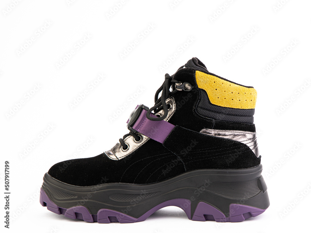 Women's black, purple and yellow hiking boots isolated white background. Left side view. Fashion shoes. Photoshoot for shoe shop concept.