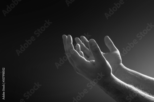 Praying hands with faith in religion and belief in God on dark background. Power of hope, love and devotion.