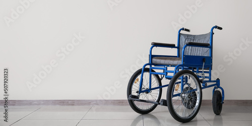 Empty wheelchair near light wall