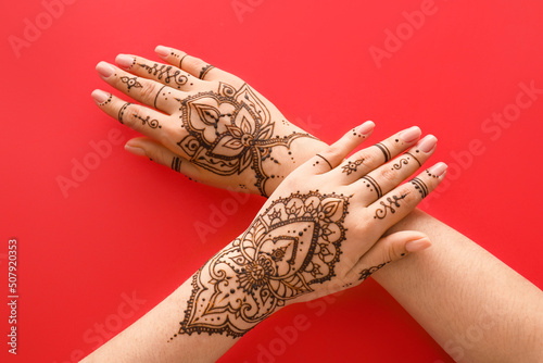 Female hands with beautiful henna tattoo on color background