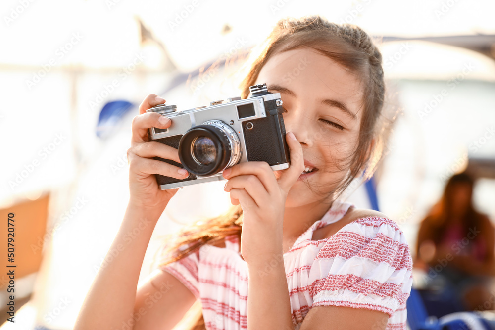 Cute little girl with photo camera resting on yacht