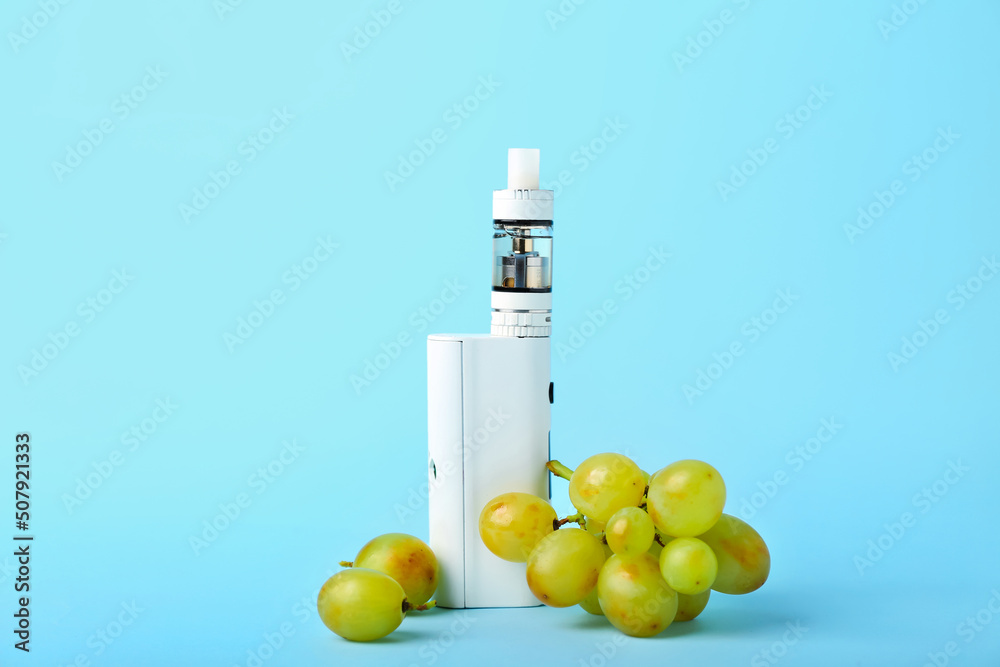 Modern vape mod and grape on blue background Modern vape mod and grape on blue background