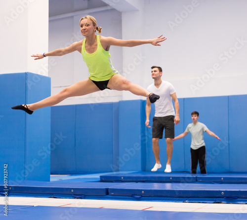 Portrait of focused sports girl during training in trampoline center. Skills and drills of side split.. © JackF