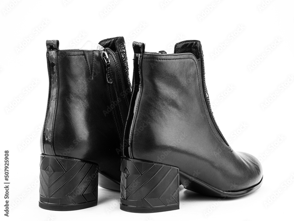 Women's autumn ankle black leather boots with black zip and average heels, isolated white background. Back side view. Fashion shoes. Women's autumn ankle black leather boots with black zip and average heels, isolated white background. Back side view. Fashion shoes.