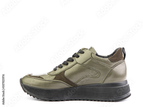 Green leather classic sneakers with laces. Casual men's style. Black rubber soles. Isolated close-up on white background. Left side view.