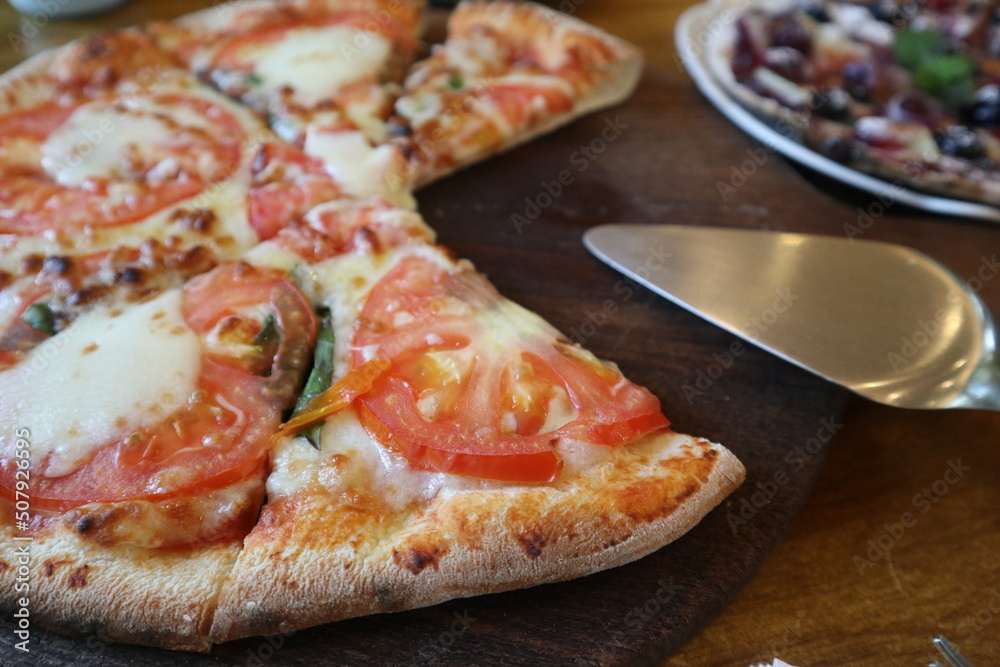 eating delicious Pizza Margherita on the wooden plate close-up with pizza cutter eating delicious Pizza Margherita on the wooden plate close-up with pizza cutter
