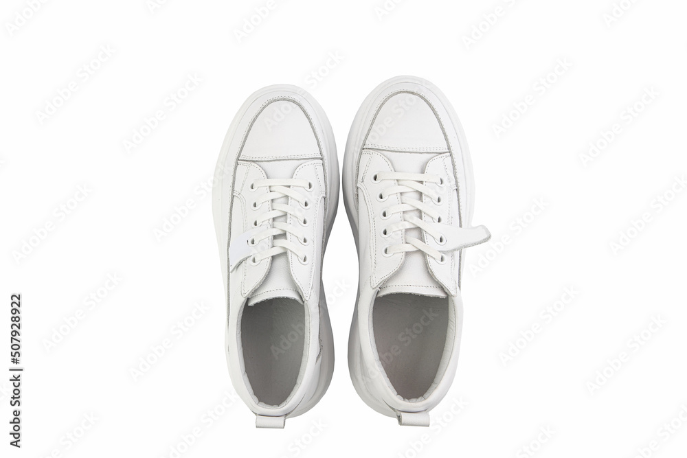 White leather sneakers. Casual women's style. White lacing and white rubber soles. Isolated close-up on white background. Top view. Fashion shoes