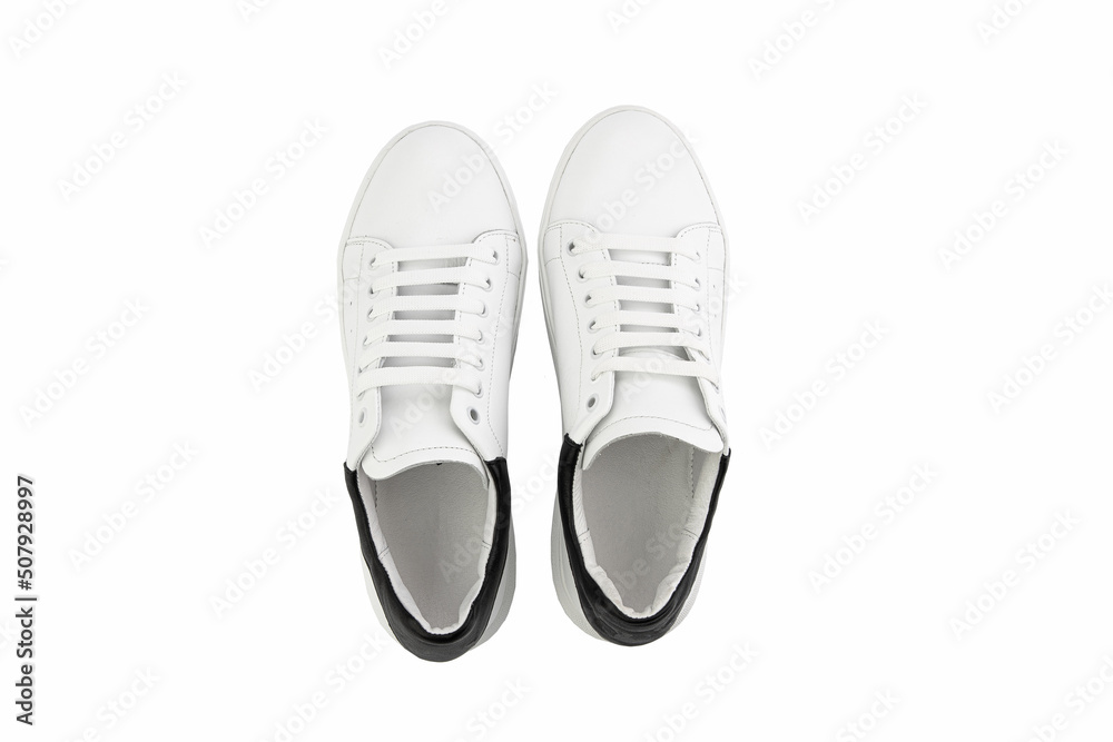 White leather sneakers. Casual women's style. White lacing and white rubber soles. Isolated close-up on white background. Top view. Fashion shoes