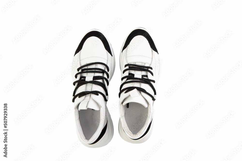 White leather sneakers. Casual women's style. White lacing and white rubber soles. Isolated close-up on white background. Top view. Fashion shoes