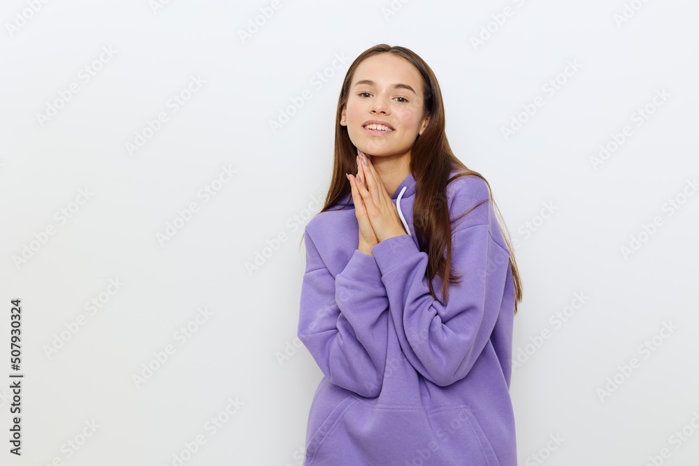 a delightful attractive woman stands half-turned on a white background in a purple tracksuit, holding her hands joined together against herself, smiling happily a delightful attractive woman stands half-turned on a white background in a purple tracksuit, holding her hands joined together against herself, smiling happily