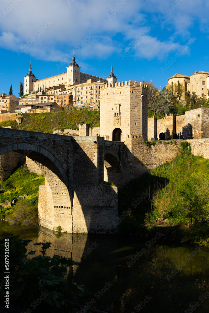 Picturesque view of Alcazar fortress and Alcantara bridge over Tagus river at old Spanish town of Toledo