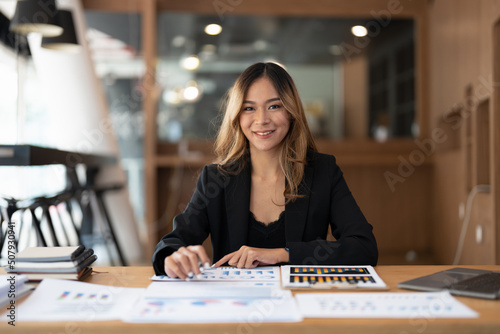 Portrair accountant asian woman working and analyzing financial reports project accounting with chart graph and calculator in modern office : finance and business concept.