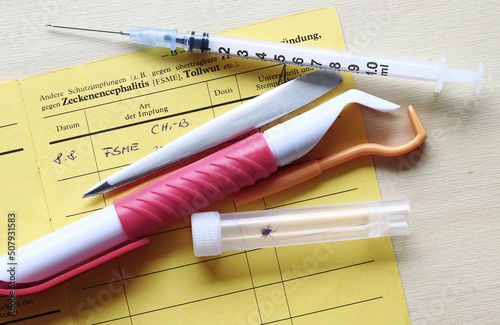 Impfung gegen Zeckenencephalitis mit Impfpass, Spritze und Zeckenzangen