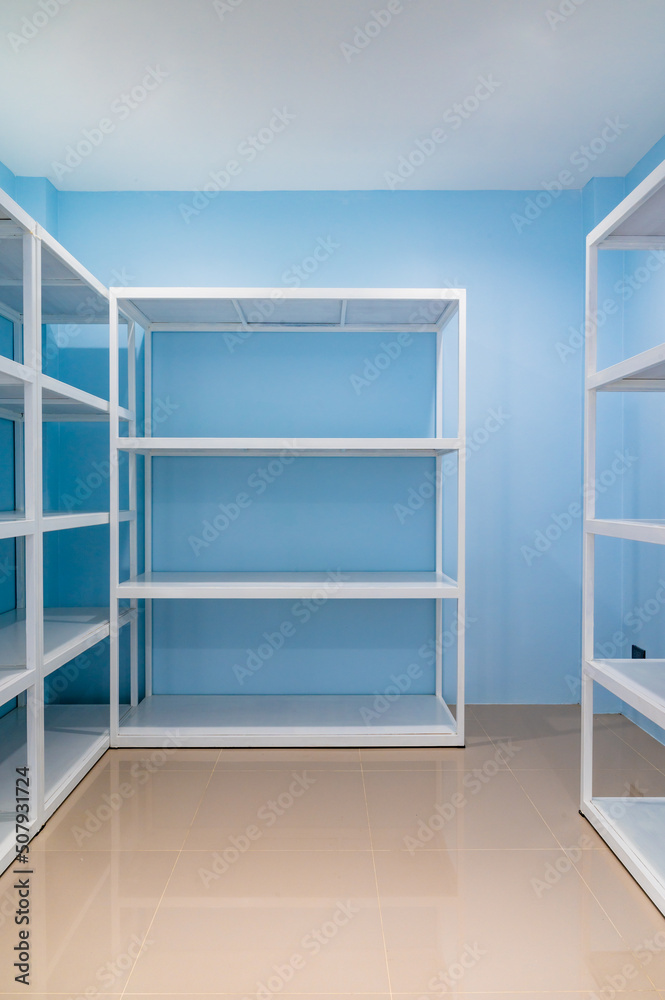 Empty white shelves in blue storage room Empty white shelves in blue storage room