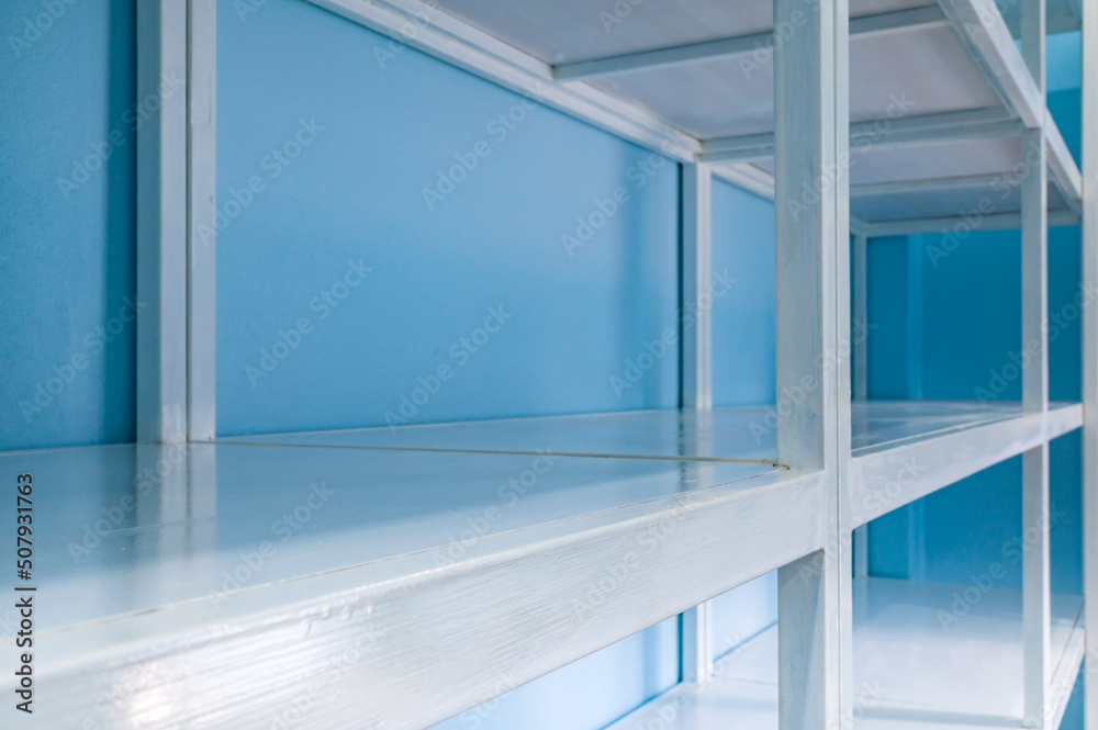 Obraz premium Empty white shelves in blue storage room