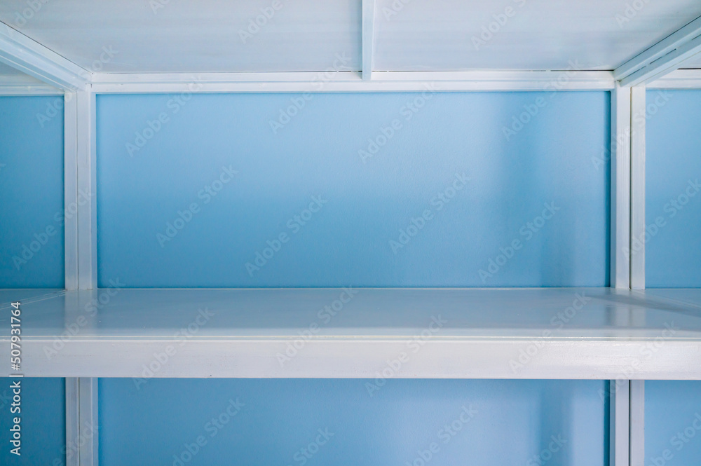 Fototapeta premium Empty white shelves in blue storage room