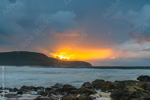 Soft sunrise seascape with rocks and rain clouds