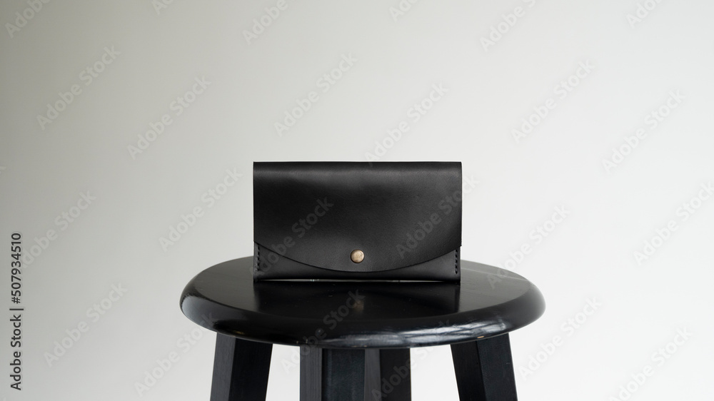 Man's handmade genuine leather wallet for banknotes and credit cards on a black surface with white background. Style, retro, fashion, vintage and elegance. Man's handmade genuine leather wallet for banknotes and credit cards on a black surface with white background. Style, retro, fashion, vintage and elegance.
