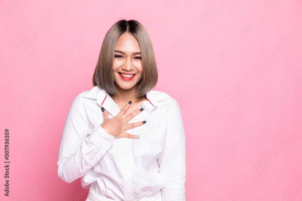 Lovely young woman presses palms to heart, feels touched and grateful, looks with admiration at something, keeps all good memories, dressed in white shirt, isolated over pink background Lovely young woman presses palms to heart, feels touched and grateful, looks with admiration at something, keeps all good memories, dressed in white shirt, isolated over pink background