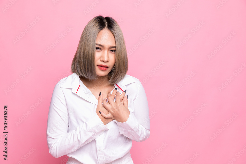 Woman touching chest. Heart attack, heart disease, and chest pain concepts, isolated on pink background Woman touching chest. Heart attack, heart disease, and chest pain concepts, isolated on pink background