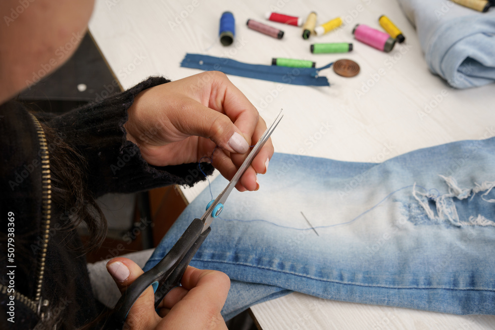 cutting a thread with scissors, seamstress workplace, jean garment repair, lifestyle and occupations, tools
