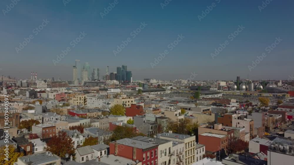 Fly over residential borough, rows of colourful apartment houses. Industrial facility and high rise buildings in distance. New York City, USA Fly over residential borough, rows of colourful apartment houses. Industrial facility and high rise buildings in distance. New York City, USA