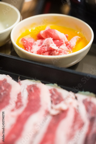 Slice beef dip in raw egg for cooking sukiyaki