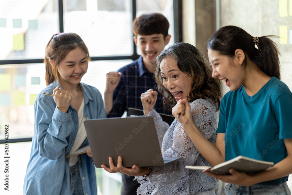 Diverse group of smiling young business people celebrating success with high fives while working together in a modern office, colleagues celebrate shared business success or victory in office.